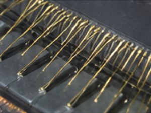 Close-up of piano strings and tuning pins above the keyboard, showing the golden strings across the dark action.